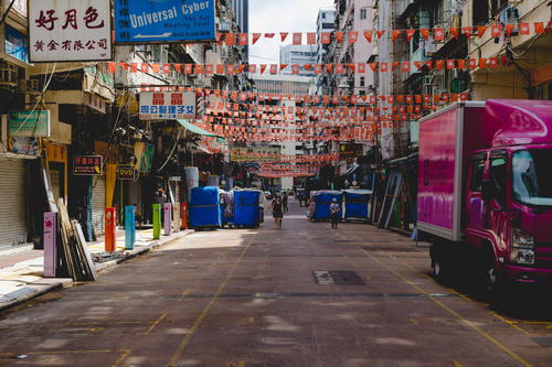 A pink truck parked on a Hong Kong street.