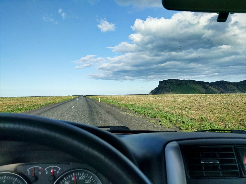 The view from the driver's seat of a car on a highway in Iceland.