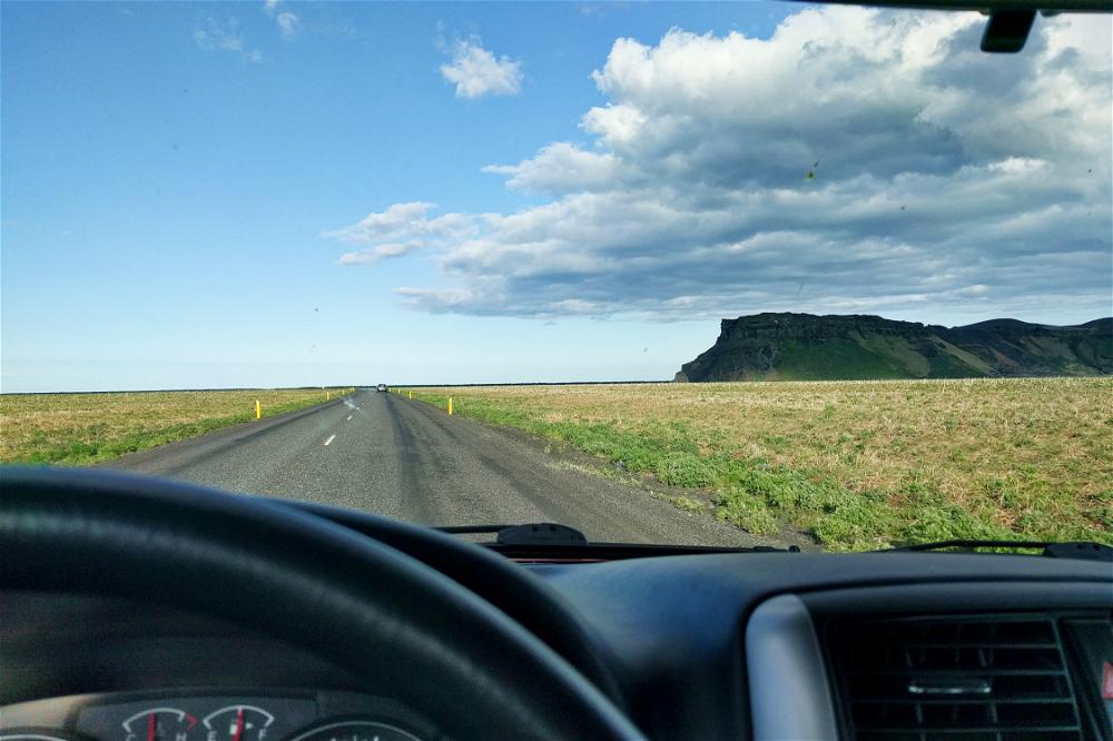 The view from the driver's seat of a car on a highway in Iceland.