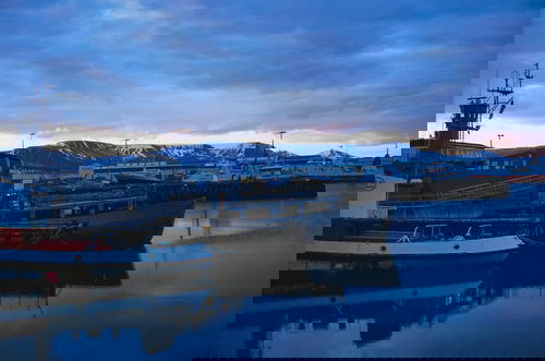 Boats docked in an Icelandic harbor with mountains in the background.