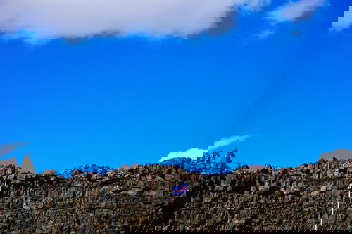 A flag is flying over a rocky cliff in Iceland.
