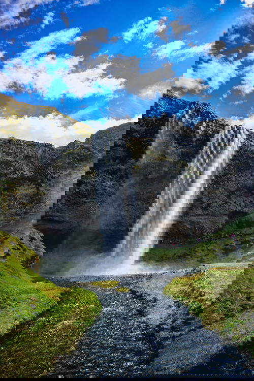 A waterfall in Iceland with a blue sky.