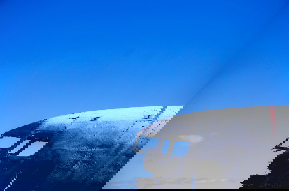 An old airplane sitting on a field in Iceland with a blue sky.