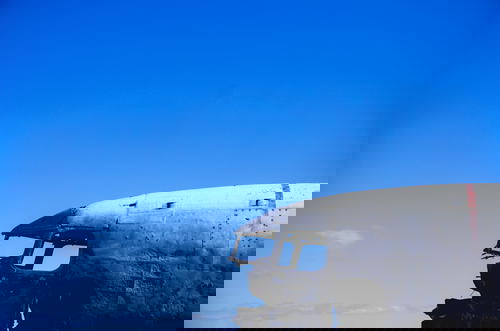 An old airplane sitting on a field in Iceland with a blue sky.