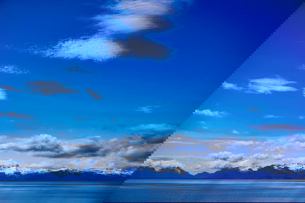 A blue sky with clouds over a body of water in Iceland.