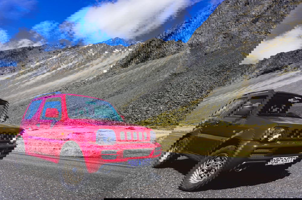 A red SUV is parked in front of a mountain in Iceland.