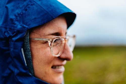 A woman wearing glasses embraces the beauty of the Wild Atlantic Way in Ireland.
