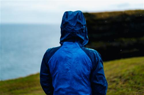 A person in a blue jacket standing on a hill overlooking the Wild Atlantic Way in Ireland.