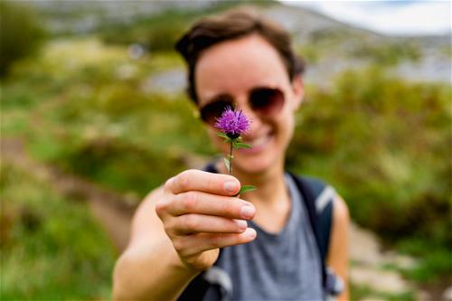 A woman holding a purple flower on the Wild Atlantic Way.