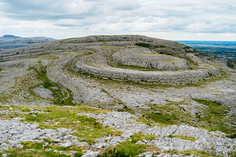 A rocky hillside with grass along the Wild Atlantic Way in Ireland, under a cloudy sky.