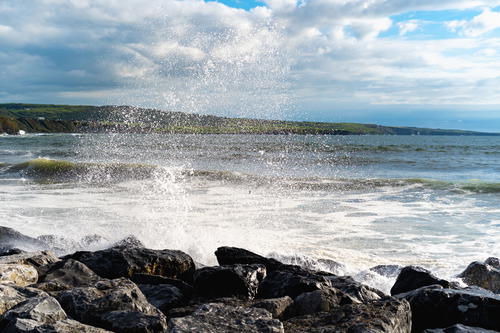 A person standing on a rocky shore along the Wild Atlantic Way in Ireland.