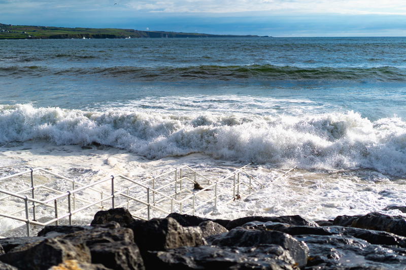 A person is standing on a rocky beach along the Wild Atlantic Way in Ireland.