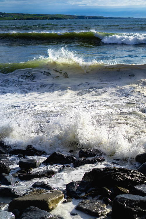 A man is standing on the Wild Atlantic Way with a surfboard.