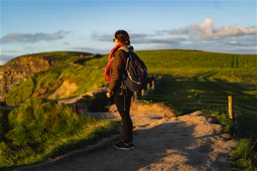 A woman hiking along the Wild Atlantic Way in Ireland with a backpack.