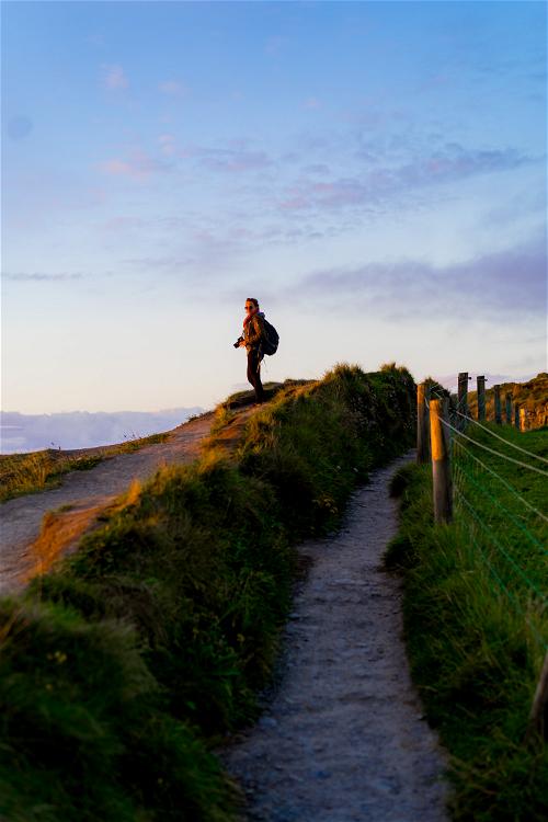 A person hiking along the Wild Atlantic Way in Ireland with a backpack.