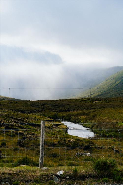 A Wild Atlantic Way field with a fence and a stream in the background.