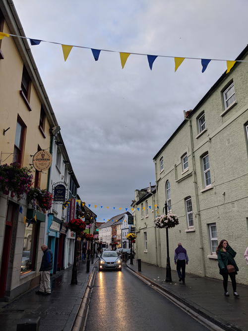 People walking down a street with Irish flags hanging from the buildings along the Wild Atlantic Way.