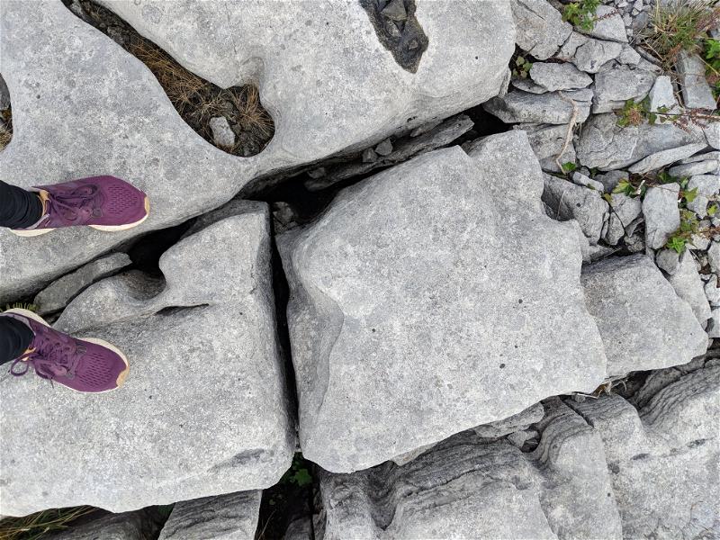 A person's feet standing on top of rocks along the Wild Atlantic Way in Ireland.
