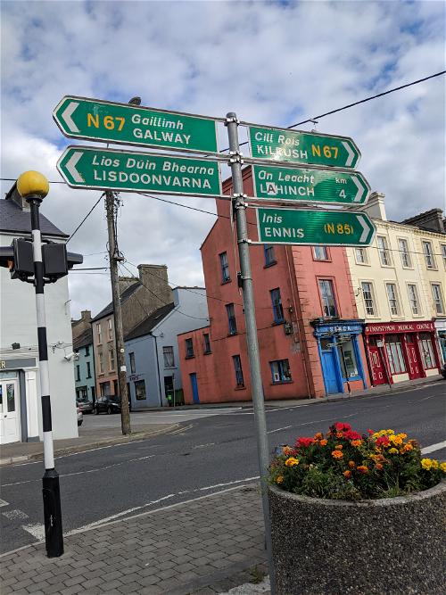 A cluster of street signs on a pole in a charming Irish town along the Wild Atlantic Way.