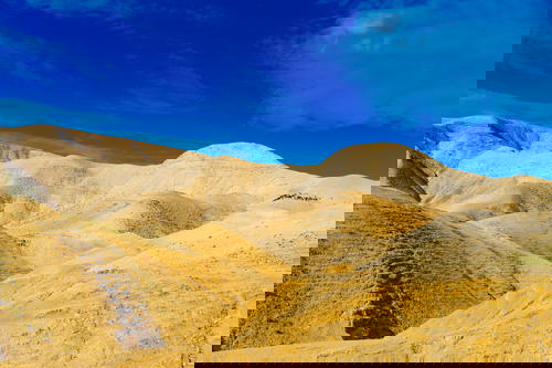 A yellow hill in Israel with a blue sky.