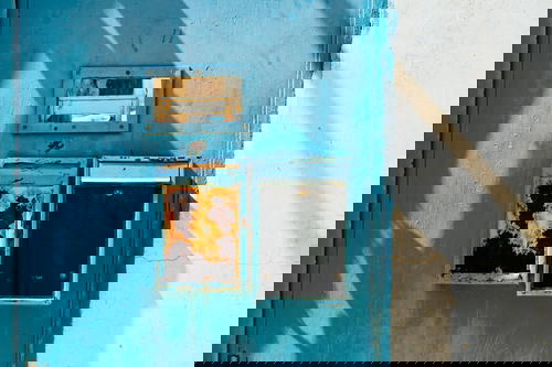 Bright blue painted door with rusted vertical mailboxes next to a white wall