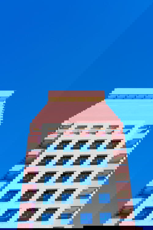 A pink and white building in Israel with a blue sky.