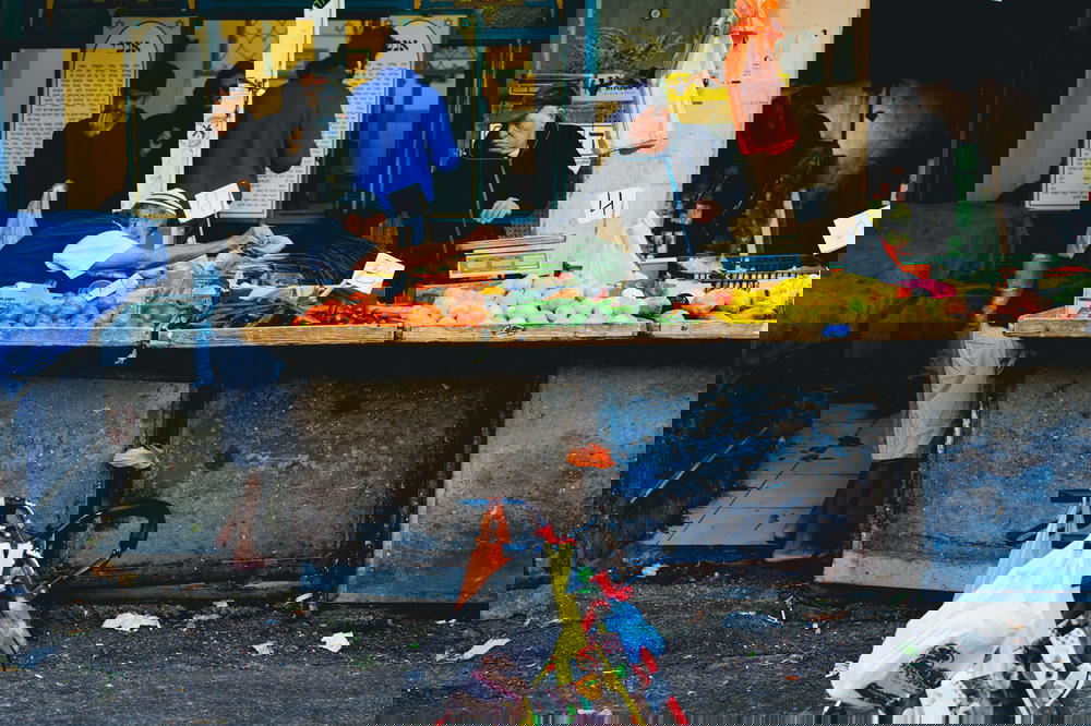 A man with a bicycle in front of a fruit stand in Israel.