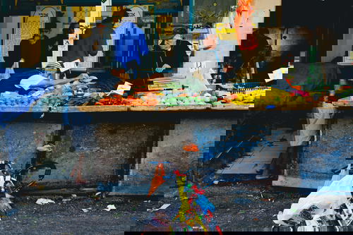 A man with a bicycle in front of a fruit stand in Israel.