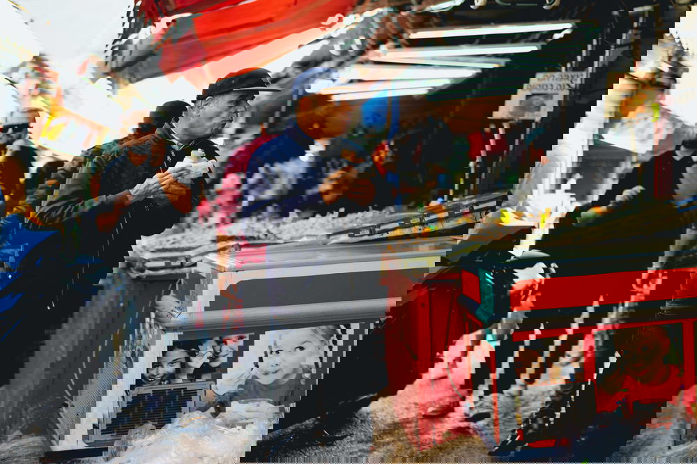 A man standing in an Israeli market with a cup of coffee.