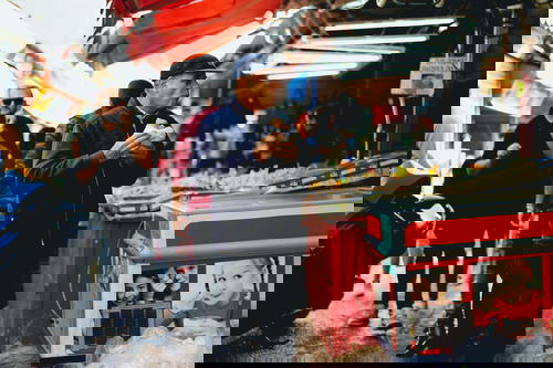 A man standing in an Israeli market with a cup of coffee.