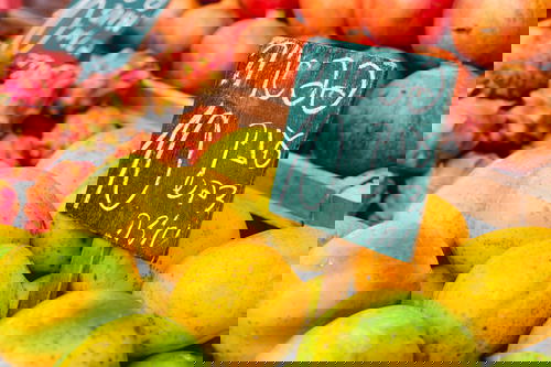 Blackboard sign in Hebrew writing placed among mangos and dragon fruits in an Israeli market