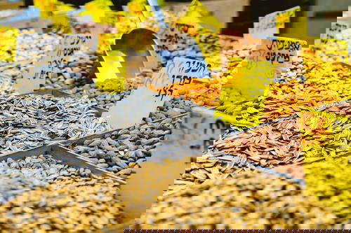 Yellow signs with black Hebrew writing for sunflower seeds and nuts at a market