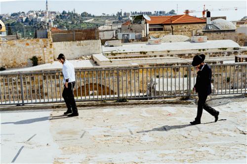 Two men walk on a stone rooftop in Jerusalem Old City