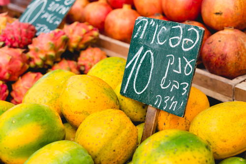 Blackboard sign in Hebrew writing placed among mangos and dragon fruits in an Israeli market