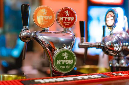 Red, yellow and green beer names in Hebrew at a bar counter