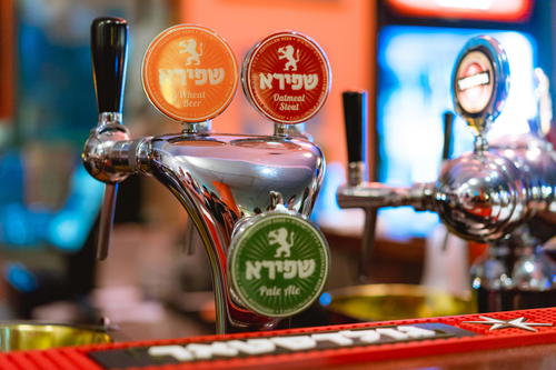 Red, yellow and green beer names in Hebrew at a bar counter