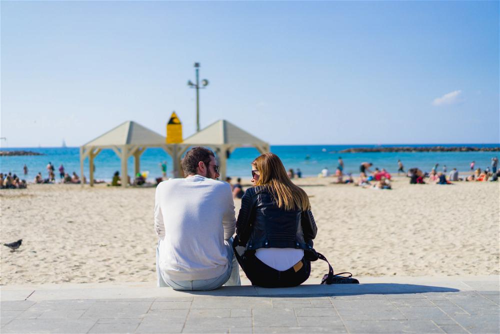 A couple sitting on the beach in Tel Aviv, Israel