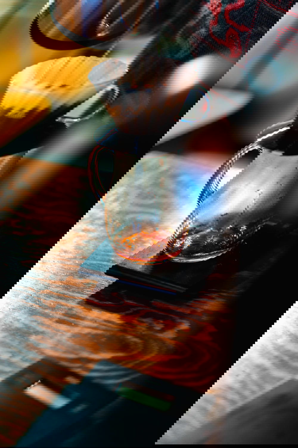 V60 pourover dripping coffee into a glass carafe on a wooden table at a coffee bar