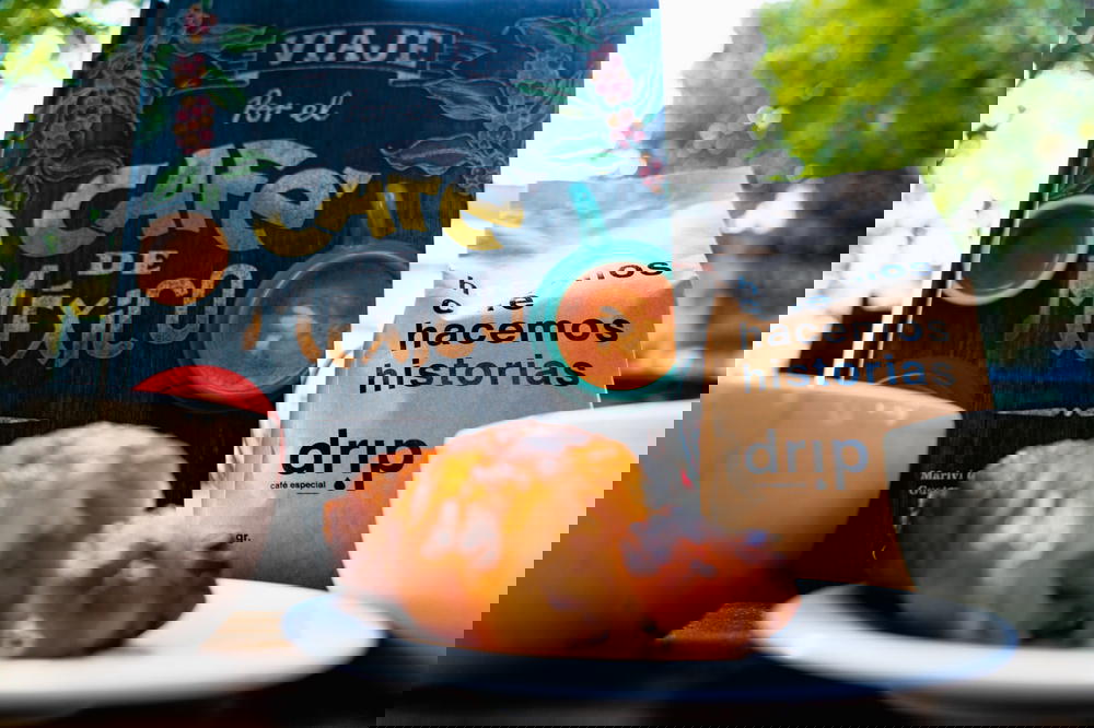 A cup of Mexican coffee and a bag of pastries on a table.