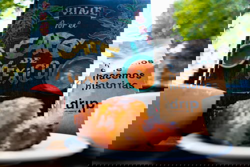 A cup of Mexican coffee and a bag of pastries on a table.