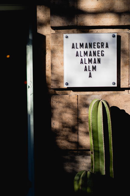 Almanegra sign with black letters on a white piece of glass outside the cafe in Mexico City