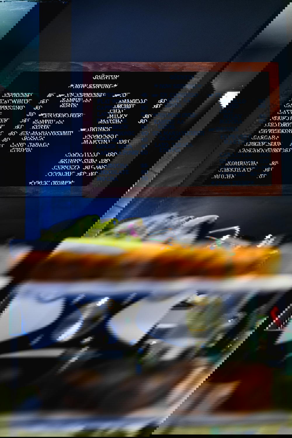 Quentin Cafe menu on a black wall at the back of the coffeshop in Mexico City