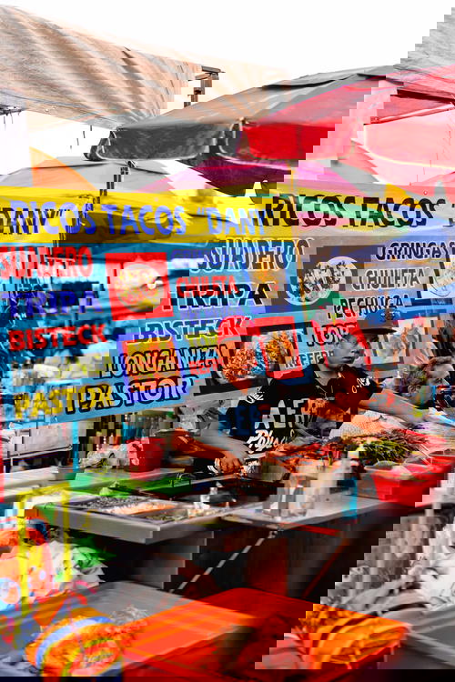 Taco vendor at a market in Mexico City in front of a sign