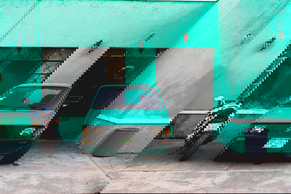 Vintage turquoise old car and old motorcycle with teal walls in Valladolid Mexico Yucatan peninsula
