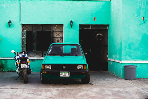 Vintage turquoise old car and old motorcycle with teal walls in Valladolid Mexico Yucatan peninsula