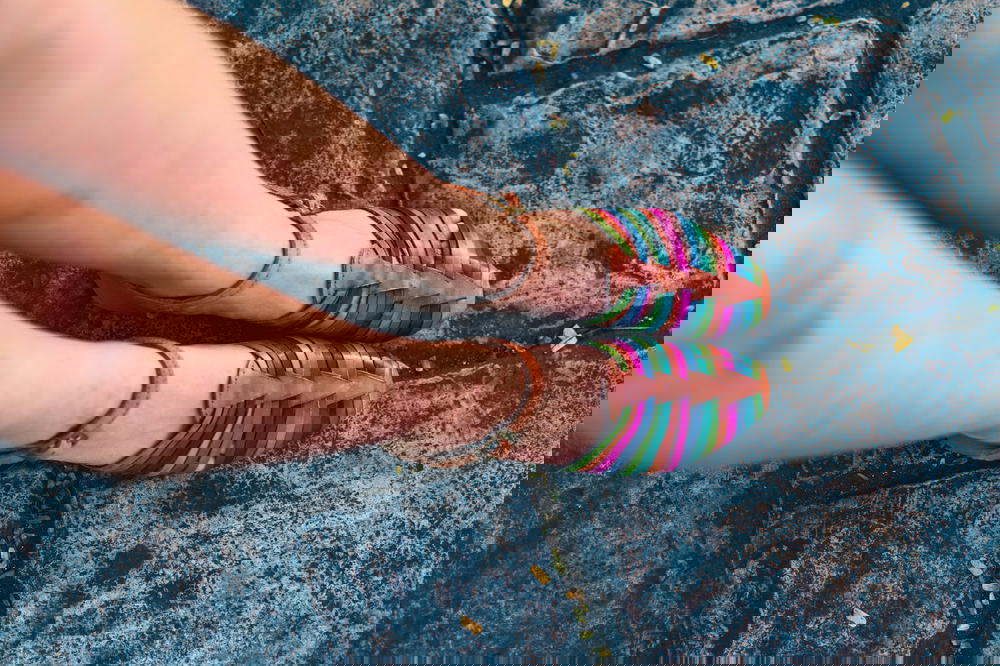 A woman's legs in colorful sandals standing on a cobblestone in Mexico.