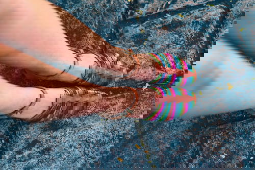A woman's legs in colorful sandals standing on a cobblestone in Mexico.