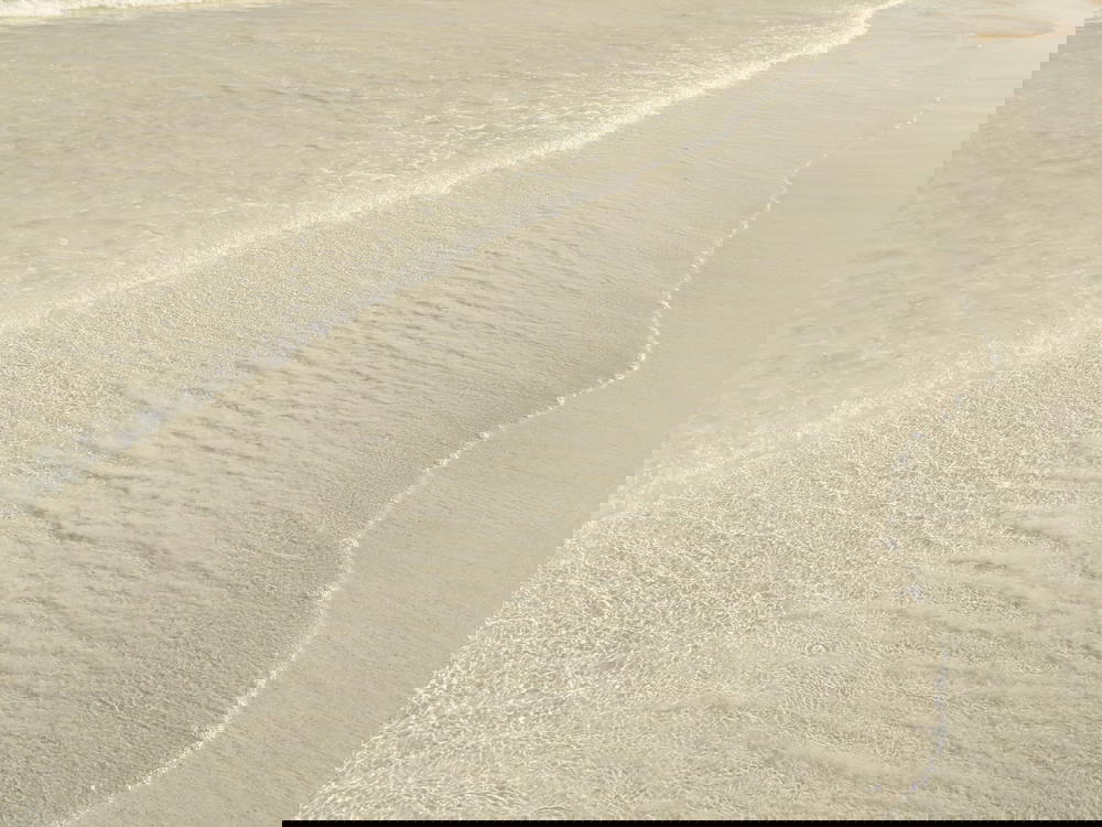 A man is standing on a beach in Mexico with a surfboard.