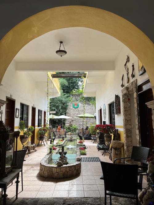 A courtyard with a fountain in the middle of it, located in Izamal, Mexico.