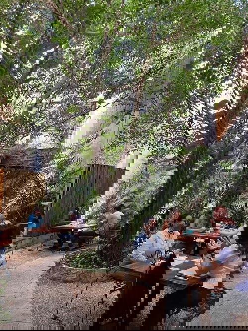 A group of people sitting at tables in a courtyard in Merida, Mexico.